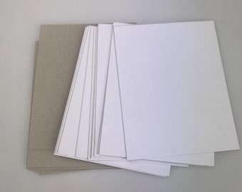 May include: A stack of white cardstock paper on top of a stack of brown cardstock paper.
