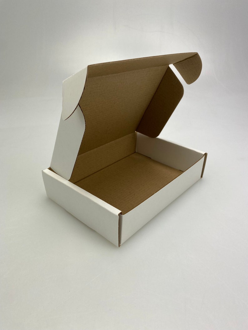 May include: A white cardboard box with the top flap open, revealing the brown cardboard interior. The box is designed for shipping and has a simple, clean design.