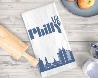 May include: White kitchen towel with a blue silhouette of the Philadelphia skyline and the text "LOVE PHILLY" in blue.