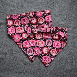 May include: Two pink and black dog bandana collars with a pattern of hearts and dogs in frames.