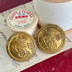 以下が含まれることがあります： 王冠と「R」と「V」の文字、その間に錨が描かれた、金色の金属製のボタンが2つ。ボタンはロープのような縁取りがされている。