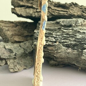 May include: A ceramic pendant with a brown and white glaze and blue accents. The pendant is shaped like a rectangle with rounded corners and has a hole at the top for hanging.