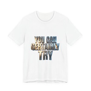 Puede incluir: Camiseta blanca con el texto "YOU CAN CERTAINLY TRY" en una fuente metálica 3D. El texto está centrado en la camiseta, que tiene cuello redondo y mangas cortas. La camiseta está hecha de un material suave y cómodo.