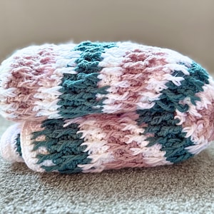 May include: A folded crocheted blanket with stripes of pink, white, and teal.