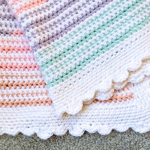 Könnte beinhalten: Zwei handgefertigte Häkeldecken. Eine Decke hat Streifen in Pfirsich, Rosa und Beige. Die andere Decke hat Streifen in Lavendel, Mintgrün und Weiß. Beide Decken haben einen weißen, gewellten Rand.