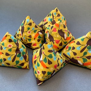 May include: Six yellow triangular fabric cushions with a toucan print. The cushions have a brown toucan with a yellow beak and blue accents on a green leafy branch with pink flowers.