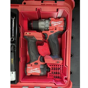 Peut inclure: Un ensemble perceuse et visseuse à percussion Milwaukee FUEL rouges dans une mallette à outils rouge. La mallette contient également une clé et d'autres outils. Les outils sont noirs et rouges.