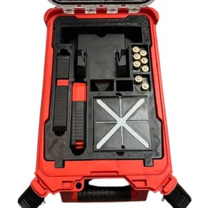 Könnte beinhalten: Ein roter Hartschalenkoffer mit schwarzem Innenraum. Der Koffer hat einen Griff und einen Verschluss. Der Innenraum des Koffers ist in Fächer unterteilt. Es befinden sich mehrere schwarze und rote Accessoires im Koffer. Außerdem befinden sich mehrere goldfarbene Kugeln in einem Fach.