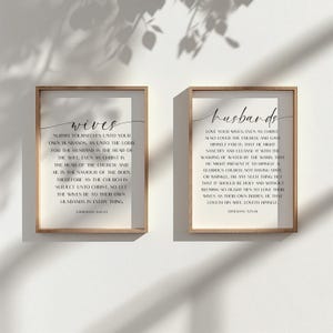 以下が含まれることがあります： 白い背景に黒い文字が書かれた額装されたプリントが2枚。左側のプリントは、上部に大きなフォントで「wives」という言葉と、エフェソス5章22-24節の聖句が書かれている。右側のプリントは、上部に大きなフォントで「husbands」という言葉と、エフェソス5章25-28節の聖句が書かれている。