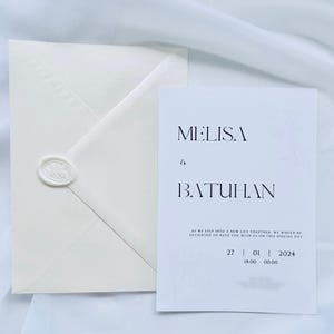 Puede incluir: Juego de invitaci&oacute;n de boda en color marfil, con un sobre sellado con un sello de cera. La tarjeta de invitaci&oacute;n presenta los nombres "MELISA & BATUHAN" y detalles del evento. Dise&ntilde;o minimalista y elegante, ideal para una boda.