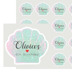 May include: A set of 12 iridescent seashell stickers with the text "Olivia's 6th Birthday". The stickers are perfect for adding a touch of whimsy to party favors, gifts, or decorations.