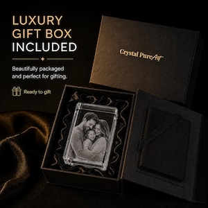 May include: A rectangular clear glass block featuring a laser-etched monochrome photograph of a family of three. The block is nestled inside a black presentation box with the gold text Crystal PureArt printed on the lid and interior.