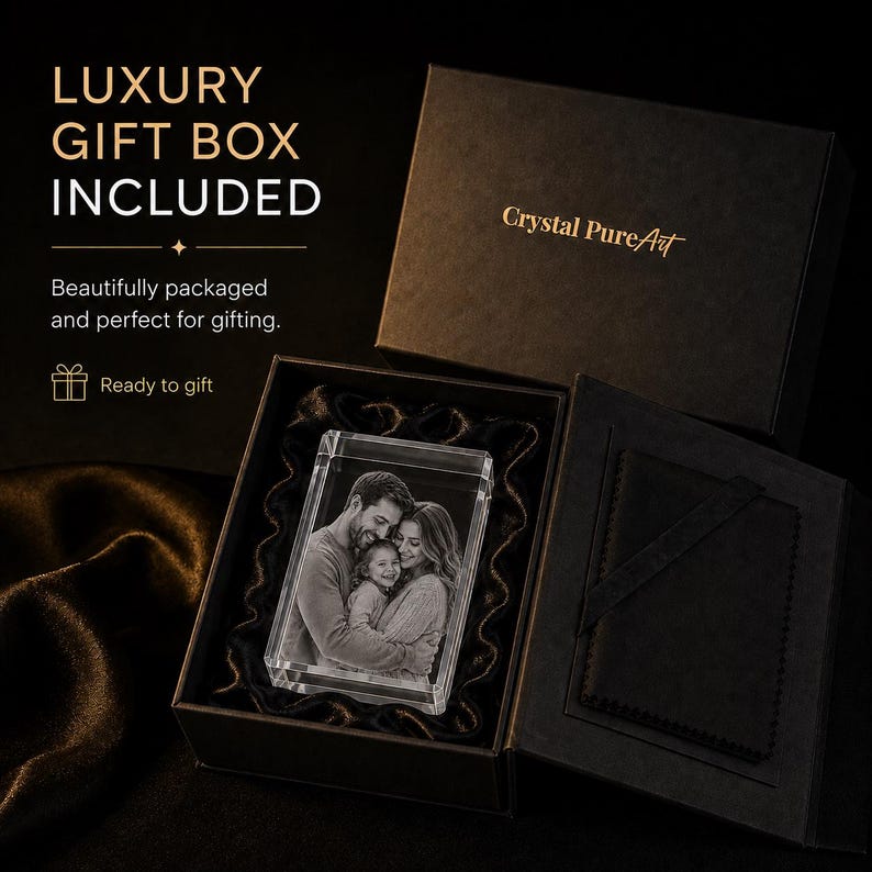 May include: A rectangular clear glass block featuring a laser-etched monochrome photograph of a family of three. The block is nestled inside a black presentation box with the gold text Crystal PureArt printed on the lid and interior.