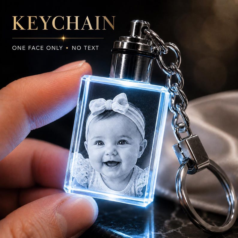 May include: A rectangular crystal keychain featuring a laser-engraved black and white portrait of a baby wearing a bow headband. The crystal is illuminated with a blue light and attached to a silver-toned metal chain and ring. Text reads KEYCHAIN.