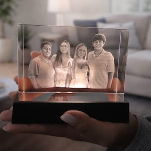 May include: A rectangular clear glass block featuring a laser-etched three-dimensional portrait of four people standing side by side. The glass block is mounted on a solid black rectangular base that illuminates the image from below.