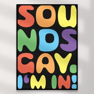 Könnte beinhalten: Ein gerahmter Kunstdruck mit dem Schriftzug "SOUNDS GAY, I'M IN!" in großen, farbenfrohen Buchstaben auf schwarzem Hintergrund. Die Buchstaben sind in Rot-, Orange-, Gelb-, Grün-, Blau-, Lila- und Türkistönen gehalten.