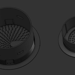 Può includere: Due coperchi di scarico in plastica nera con un design a griglia circolare. Il coperchio più grande ha un bordo rialzato e un coperchio più piccolo è inserito all'interno del più grande.
