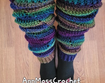 May include: A pair of handmade, colorful crochet leg warmers. The leg warmers feature a ribbed cuff and a ruffled design, with a blend of blue, green, purple, and brown yarn. The text "AnnMossCrochet" is visible.