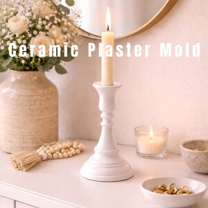 May include: A white ceramic candlestick with a lit candle, alongside a burning candle in a glass votive. The image includes a vase of flowers, a beaded tassel, and small bowls. The text on the image reads "Ceramic Plaster Mold."