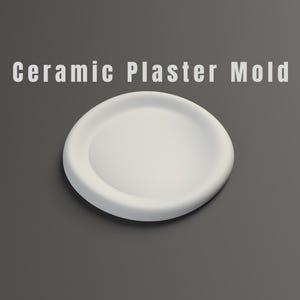 May include: A white ceramic plaster mould with a rounded shape. The mould has a shallow, dish-like design with a slightly raised edge. The text "Ceramic Plaster Mold" is displayed in white letters.