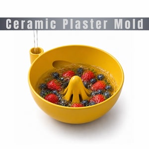 May include: A yellow ceramic bowl with a central reamer and a small side spout, filled with water, red strawberries, and dark blue blueberries. The text "Ceramic Plaster Mold" is displayed in a grey banner at the top of the image.