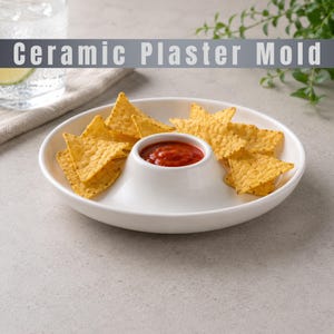 May include: A white ceramic serving dish with a central circular compartment filled with red salsa, surrounded by a wide outer rim holding yellow triangular tortilla chips. The text Ceramic Plaster Mold is visible at the top of the image.