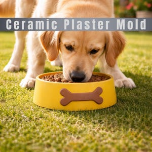Puede incluir: Un golden retriever comiendo de un cuenco amarillo para perros con un diseño de hueso marrón. El cuenco está lleno de pienso marrón y está sobre hierba verde. El texto "Ceramic Plaster Mold" se muestra encima del perro.