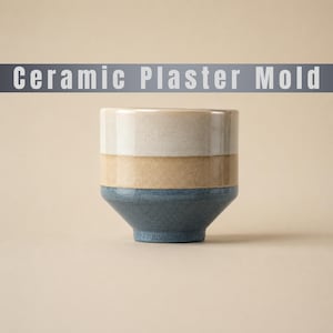 Może przedstawiać: Cylindryczna ceramiczna forma gipsowa o trójkolorowym wzorze, składająca się z kremowej górnej części, beżowego środkowego paska i ciemnoniebieskiej podstawy. Tekst "Ceramic Plaster Mold" znajduje się na szarym banerze u góry obrazu.