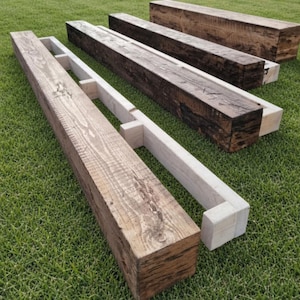 May include: Three rectangular wooden beams with a dark brown, weathered finish. Each beam features a hollow, U-shaped construction with light-colored interior support brackets visible along the length of the structure, showcasing wood grain.