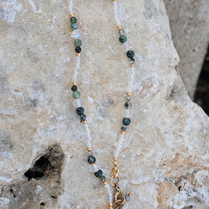 May include: A delicate ankle bracelet made with clear and green beads, with a gold clasp and extender chain. The bracelet is 10.5 to 12 inches long and is labeled "Plus Size".