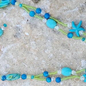 May include: A double-strand necklace with turquoise, green, and blue beads, and two starfish charms. The necklace has a silver clasp.