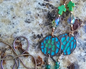 May include: A pair of teal and green eyeglass holders with a copper wire and crystal beads. The holders feature a round teal and green patterned metal charm and a green cross charm.