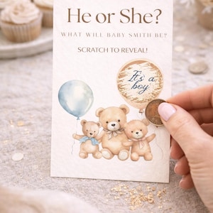May include: A gender reveal card with the text "He or She?" and "What will Baby Smith be?" The card features illustrations of teddy bears, a blue balloon, and the phrase "It's a boy". A coin is scratching the reveal area.