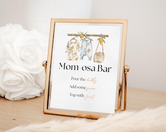 May include: A gold-framed sign with the text "Mom-osa Bar" and instructions for making a mimosa: "Pour the bubbly, Add some juice, Top with fruit". The sign features a watercolor illustration of two baby outfits hanging on a clothesline with oranges and leaves.