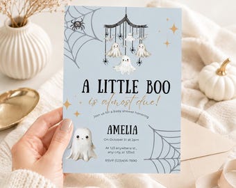 May include: A light blue baby shower invitation card featuring a mobile with hanging ghosts and spiders, a large ghost at the bottom, and spider webs in the corners. The text reads A LITTLE BOO is almost due! honouring AMELIA on October 31 at 2pm.