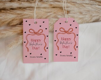 May include: Two pink gift tags with black hearts and a red bow. The text on the tags reads "Happy Valentine's Day!" and "From: Amelia".