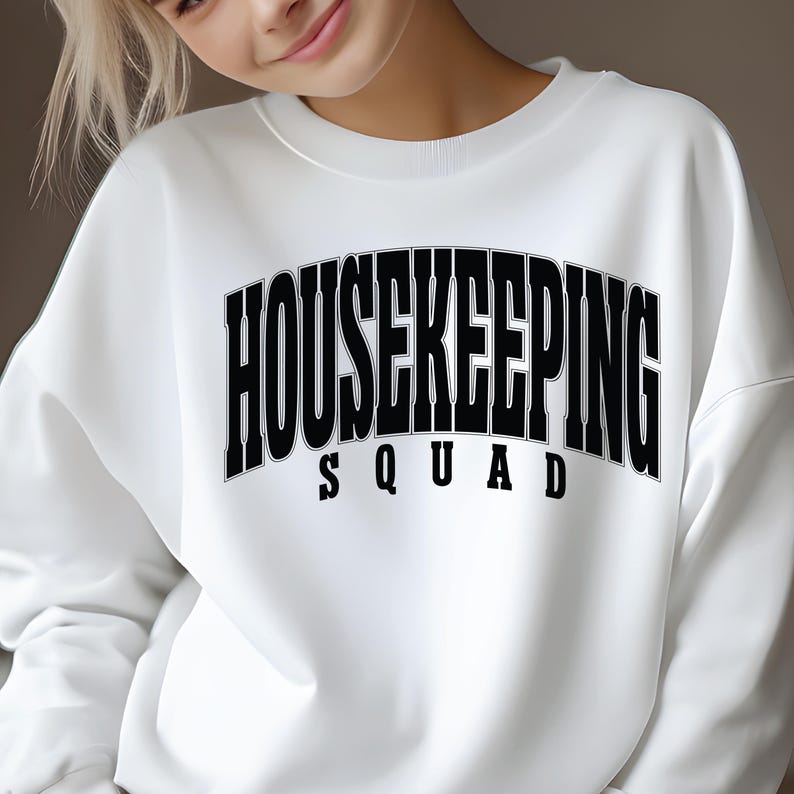 Op de afbeelding: Wit sweatshirt met zwarte tekst die "HOUSEKEEPING SQUAD" luidt.