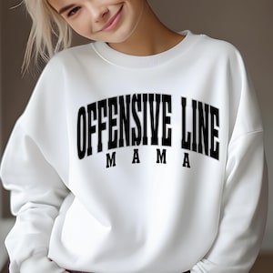 Könnte beinhalten: Weißer Pullover mit schwarzem Text, der "Offensive Line Mama" lautet.
