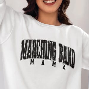May include: White sweatshirt with a black graphic that says "Marching Band Mama" in a distressed font.