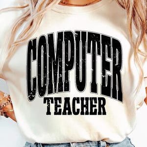 May include: Cream-colored sweatshirt with the words "COMPUTER TEACHER" printed in bold, black, distressed font. The text is arched across the top and straight across the bottom. The sweatshirt is a casual style.