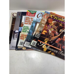 May include: A stack of craft magazines with colorful covers. Titles include "Cross Country," "Just Cross Stitch," and others. The magazines feature images of crafts, seasonal projects, and stitch patterns.