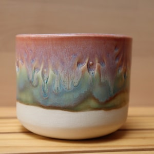 Peut inclure: Une tasse en céramique avec une base blanche, un glaçage vert et bleu et un glaçage rose et blanc sur le dessus.