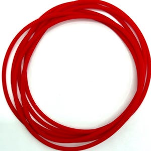 May include: Several bright red rubber O-rings are arranged in a circular pattern against a white background. The flexible, circular shape of the rings suggests a sealing or gasket function, likely for mechanical or plumbing applications.
