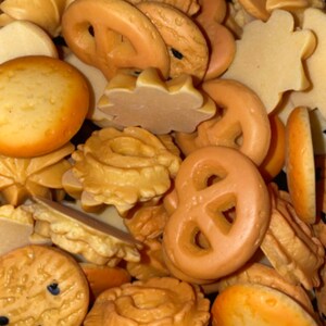 May include: A variety of brown and tan cookies and pretzels in a close-up image. The cookies are in various shapes, including round, star, and pretzel shapes.