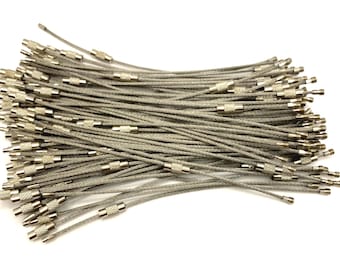 May include: A pile of silver-colored steel wire keychains with screw-on ends. The keychains are made of thin, flexible wire and have a small, cylindrical screw-on connector at each end. The keychains are on a white background.