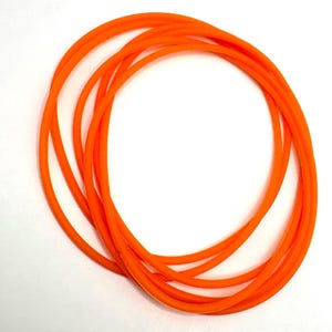 May include: Bright orange rubber O-rings arranged in a circular pattern against a white background. The O-rings are flexible and appear to be made of a durable material. The image is well-lit, highlighting the vibrant color and smooth texture of the rings.