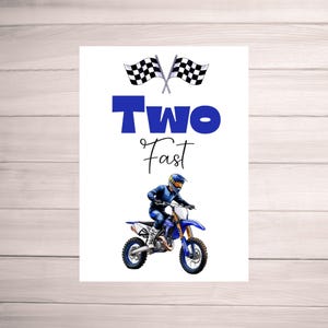 May include: A white card with blue text that says "Two Fast" and a black and white checkered flag. A blue and white dirt bike with a rider in a blue and white racing suit is in the bottom half of the card.