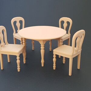May include: A miniature wooden dining set with a round table and four chairs. The table has a central pedestal base and the chairs have curved backs. The set is made of light-colored wood and is set against a dark background.