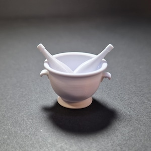 May include: A white miniature wine bucket with two white wine bottles inside. The bucket has two small handles and a pedestal base. The items are made of a smooth, solid material and are set against a dark background.