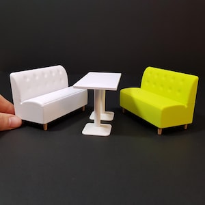 May include: A white and a lime green sofa with a white table in between. The sofas have tufted upholstery and wooden legs.